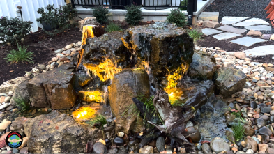 Decorative garden waterfall with glowing lights and stones.
