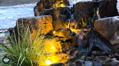 Illuminated rock waterfall in landscaped garden