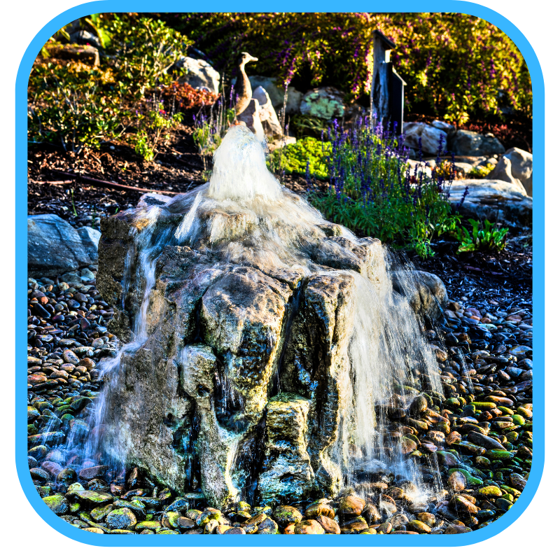 Natural stone fountain installation with driftwood and boulders showing custom basin work